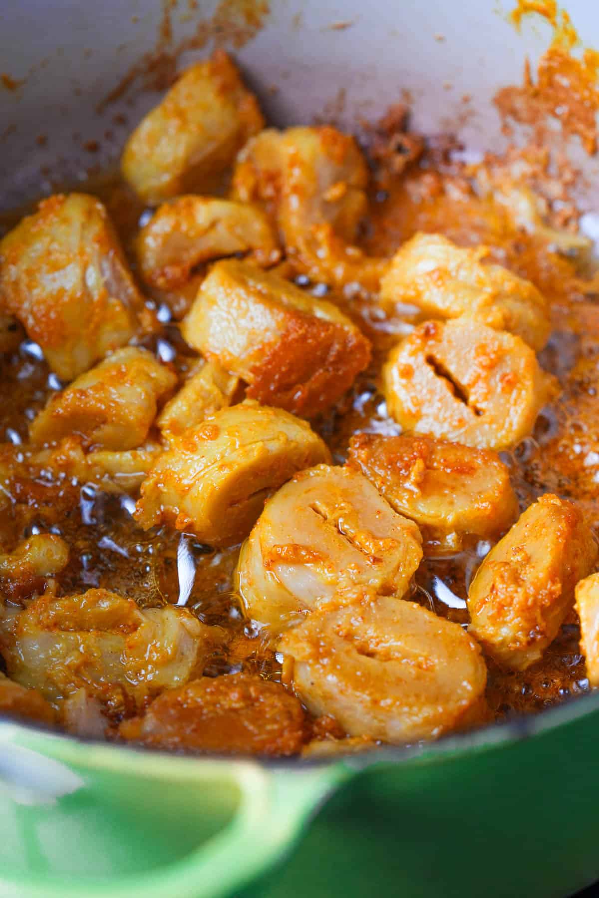 A yellow pot with marinated soya chaap frying in it.