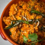 An orange bowl of soya chaap curry on a table.