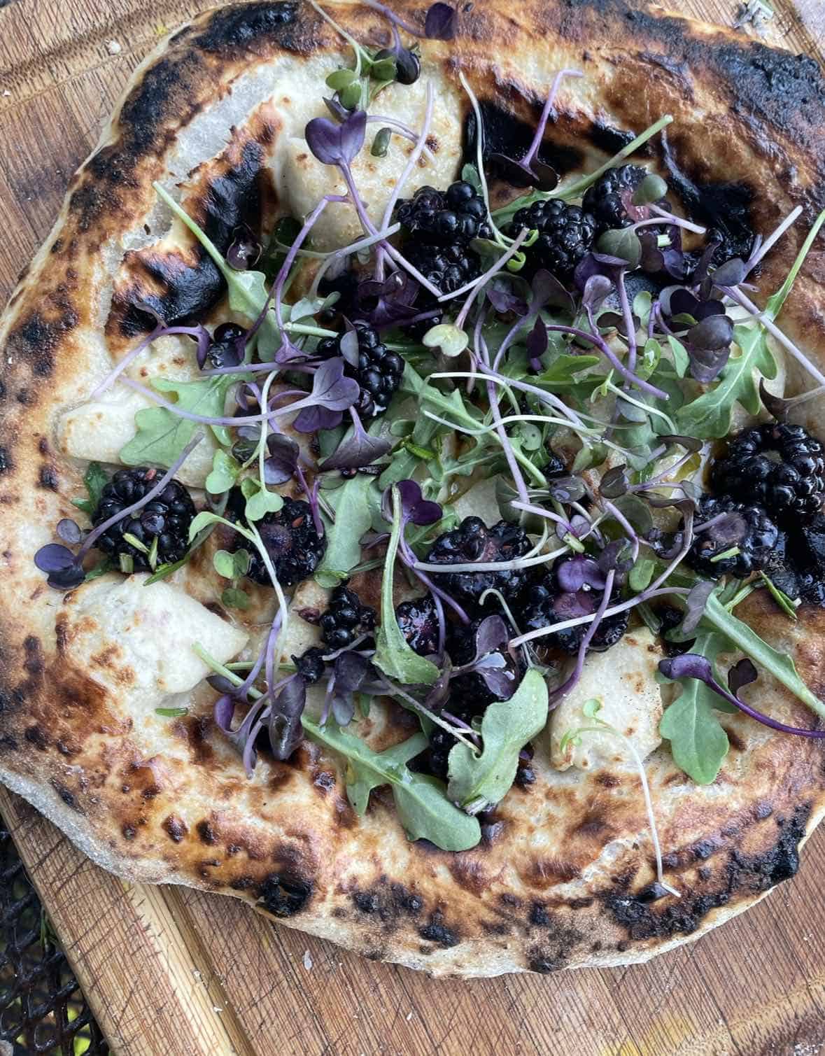 Vegan blackberry pizza on a wooden cutting board.
