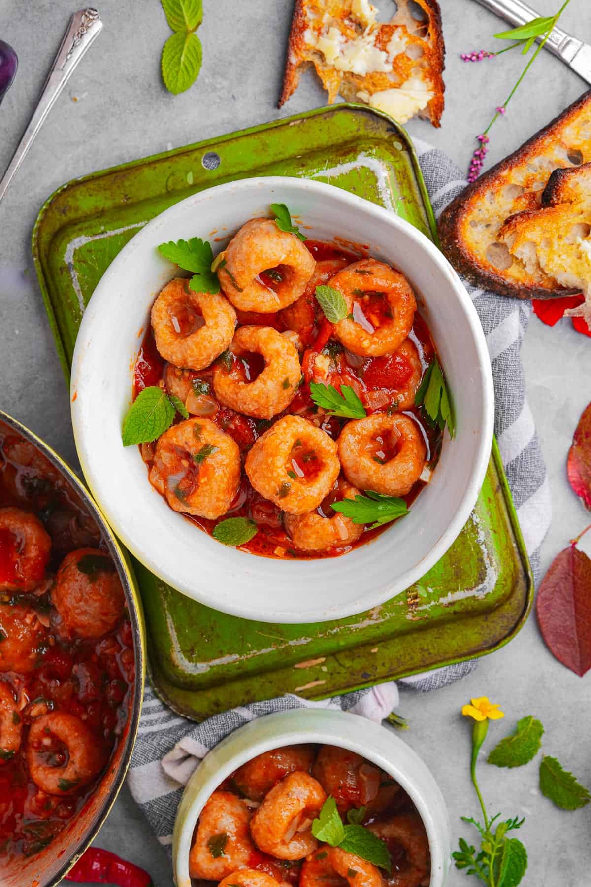 A bowl of Fellah Koftesi in tomato sauce with fresh mint and parsley.