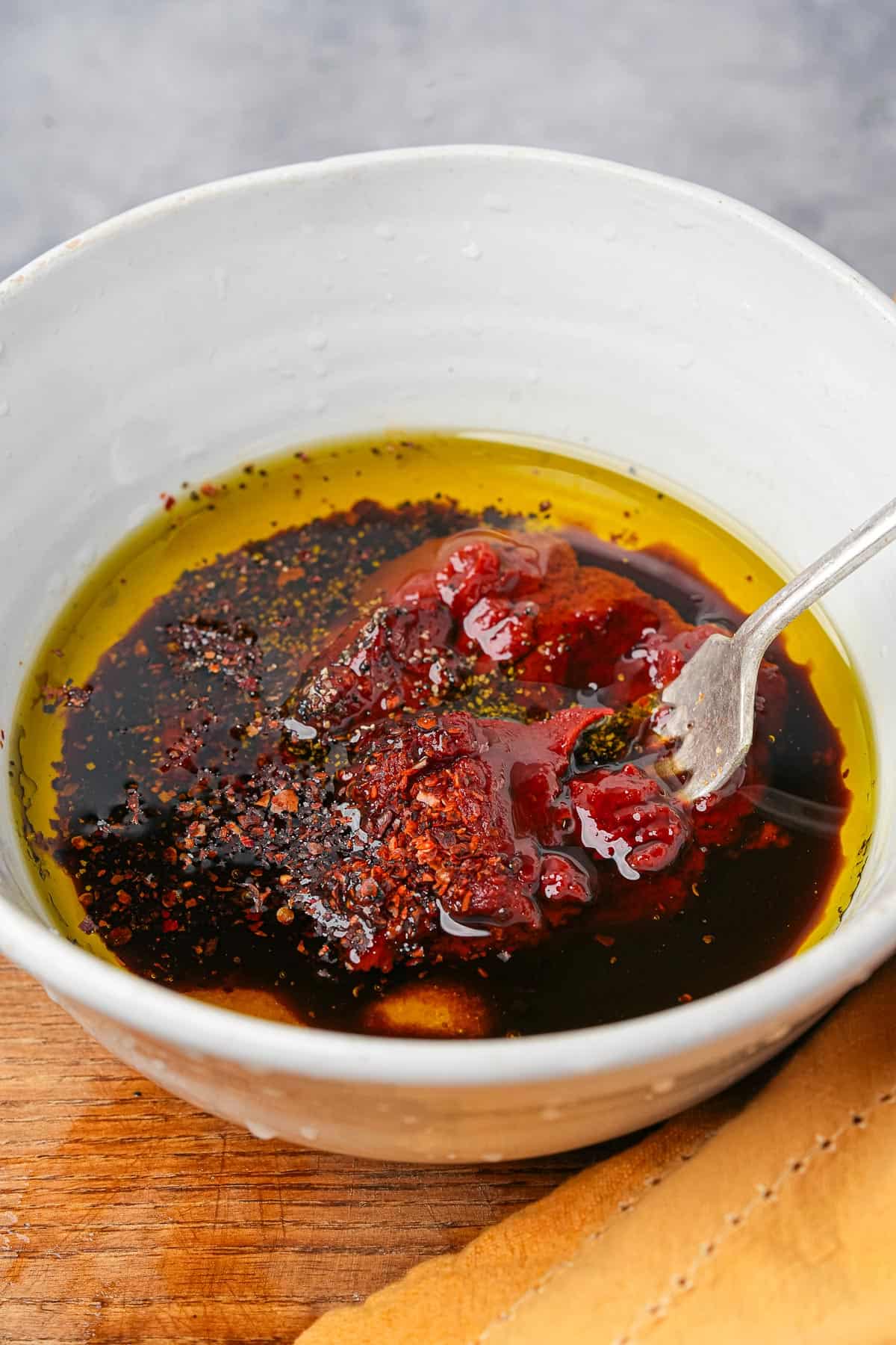 A bowl of dressing being mixed together with a fork.