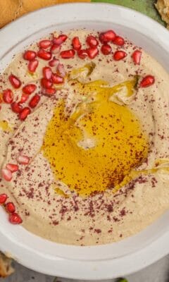 A bowl of mutabal with olive oil and pomegranate seeds.