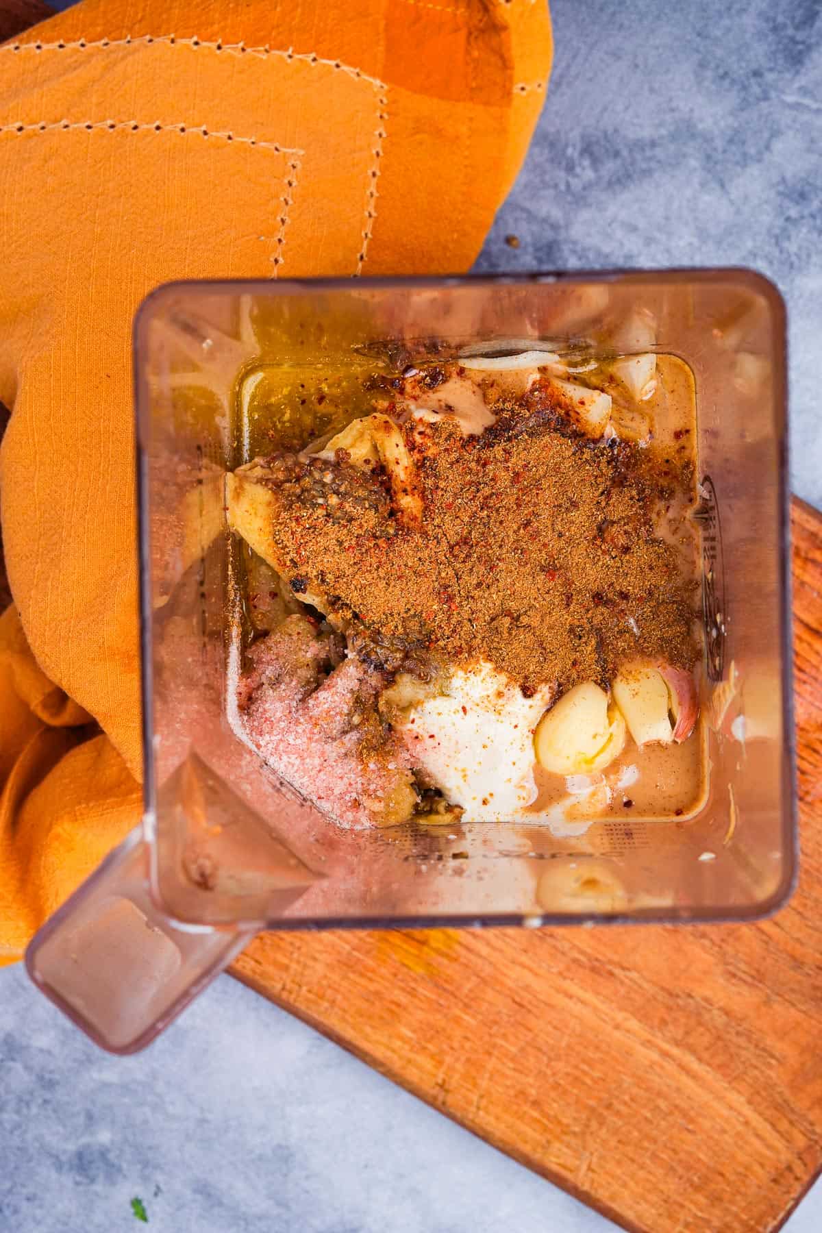 A blender filled with roasted eggplant, garlic, olive oil and spices.