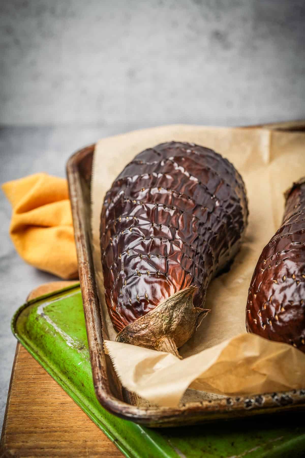 Two roasted eggplants on a baking sheet.