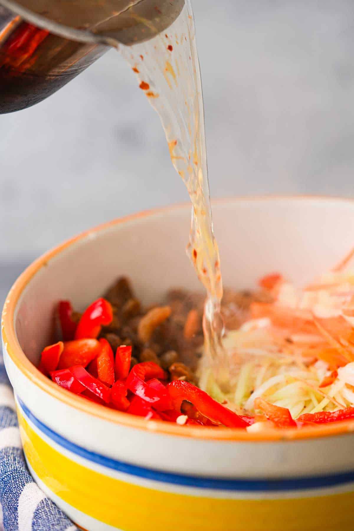A pot of hot brine is poured into a bowl of prepped achara ingredients