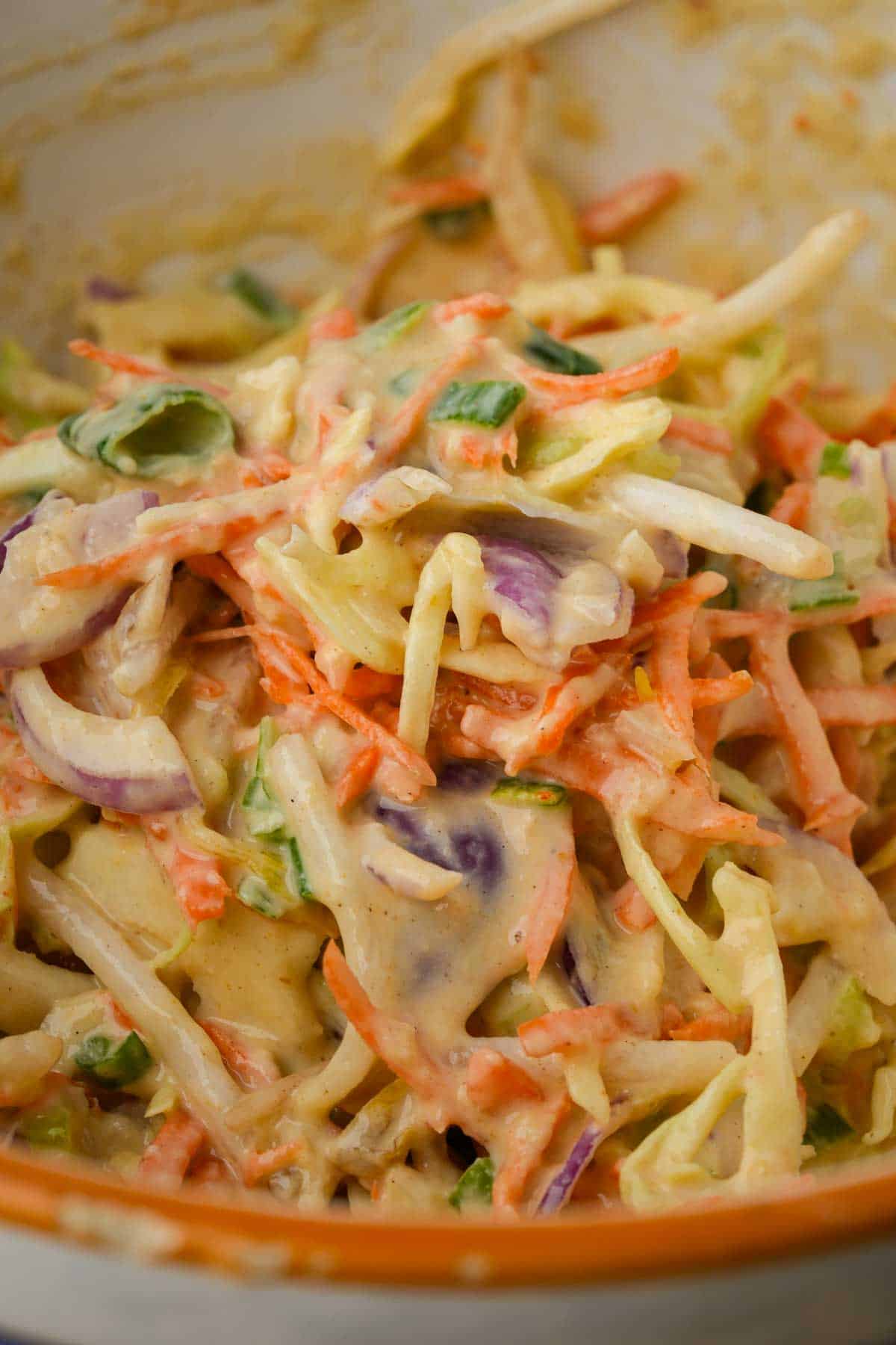 A bowl of julienne cut vegetables with batter mixed into it.