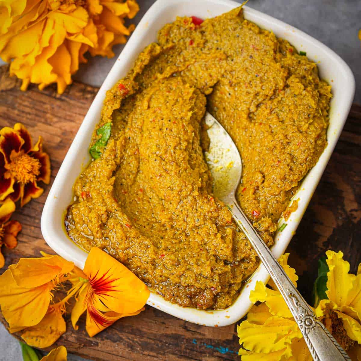 A bowl of Bumbu Bali surrounded by flowers.