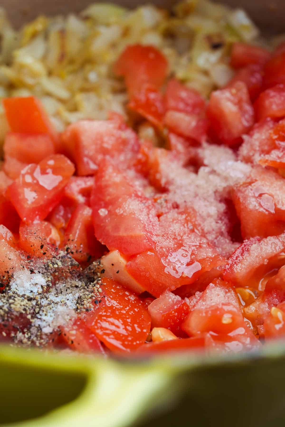A pot with tomatoes, onions, salt and pepper in it.