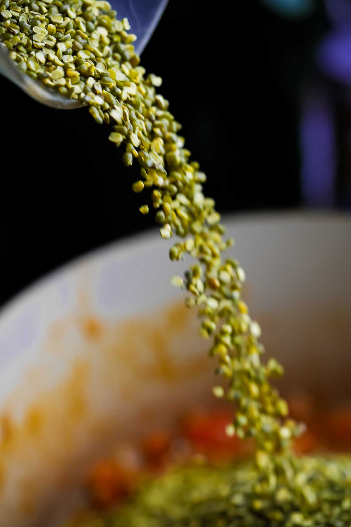 Split green mung beans being poured into a pot.