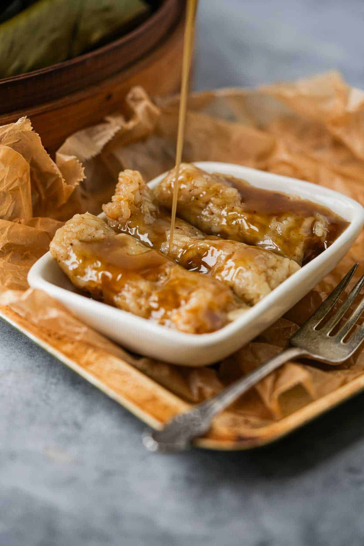 A plate of Suman Malagkit being drizzled with caramel.