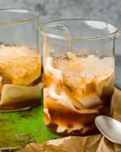 Two glass cups filled with taho on a green tray.