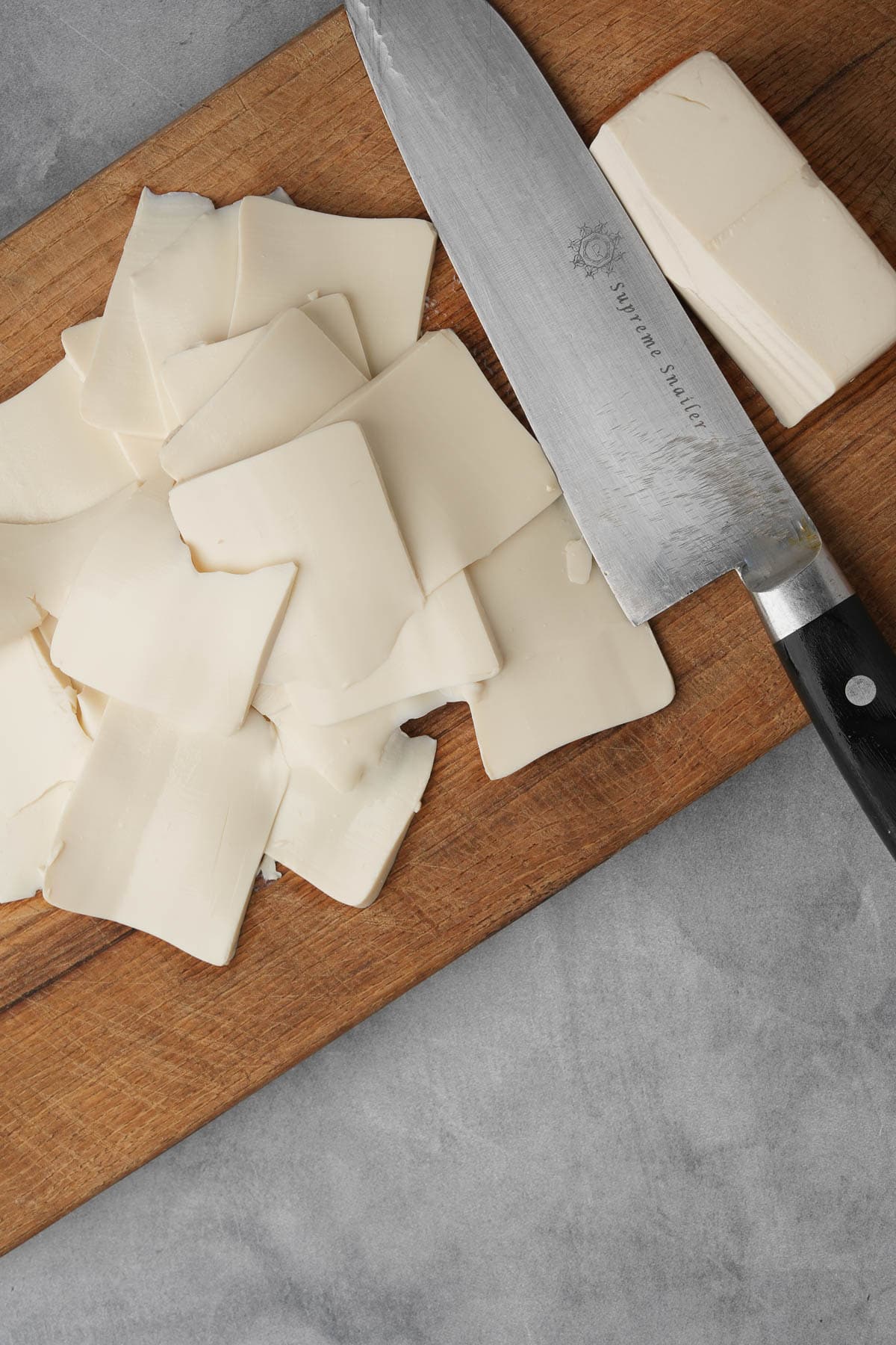 Steamed silken tofu on a cutting board with a knife.