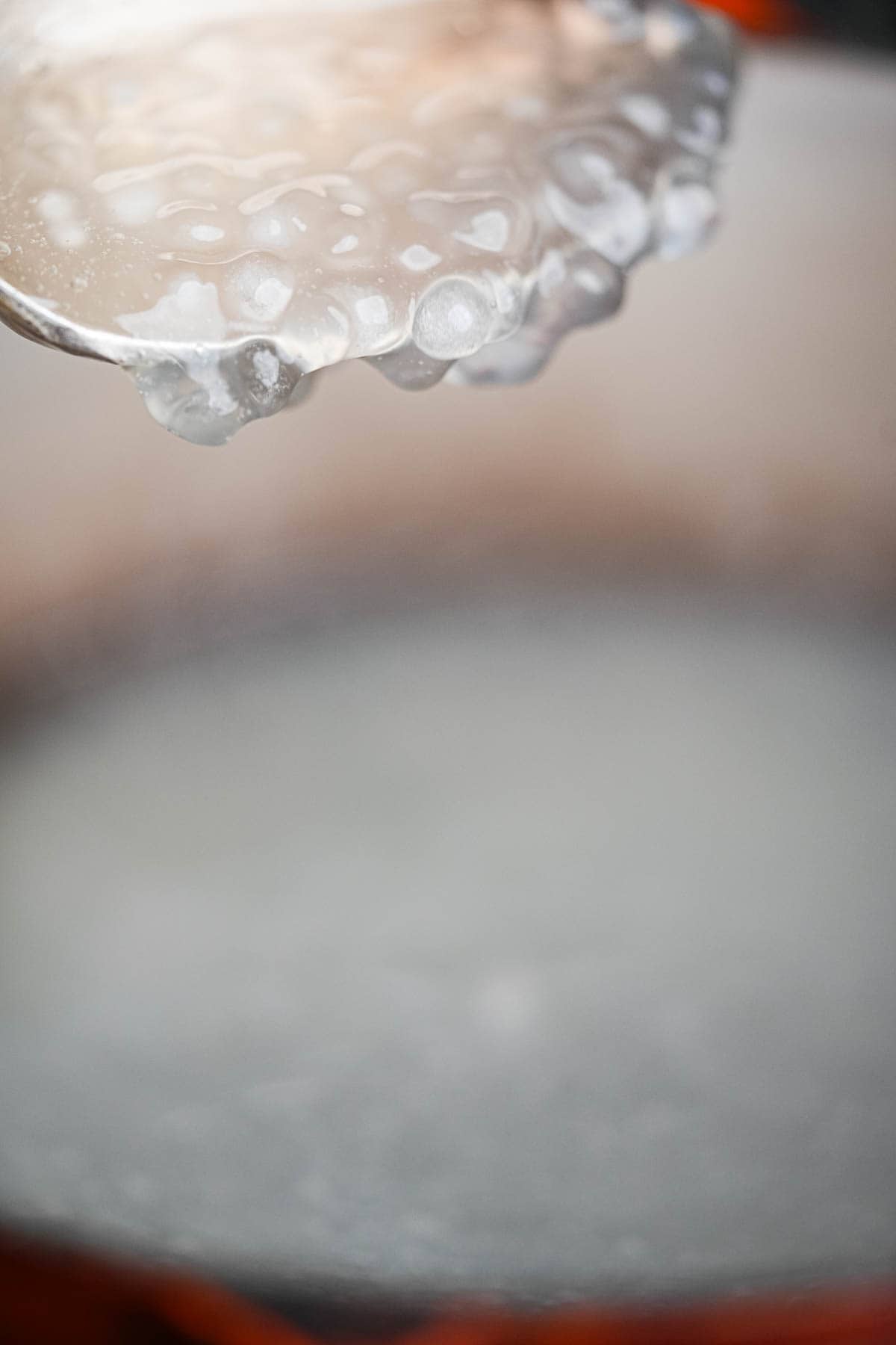 A spoon is removing cooked tapioca pearls from a pan.