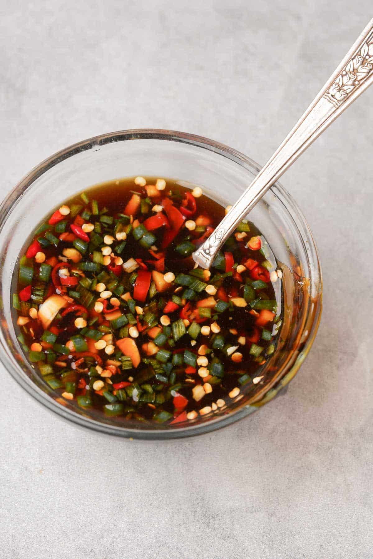 A bowl of chile sauce with a spoon in it.