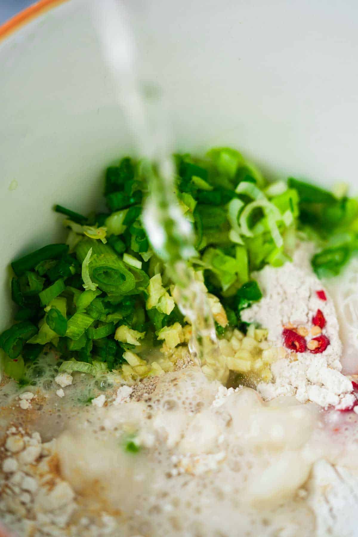 A white bowl with batter ingredients being combined in it.