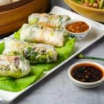banh trang cuon spring rolls on a plate with dipping sauce.