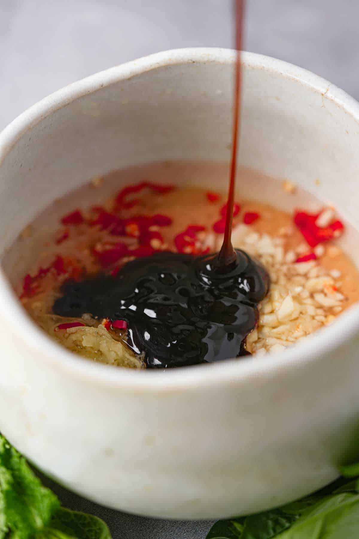 A white bowl with a sauce being poured into it.