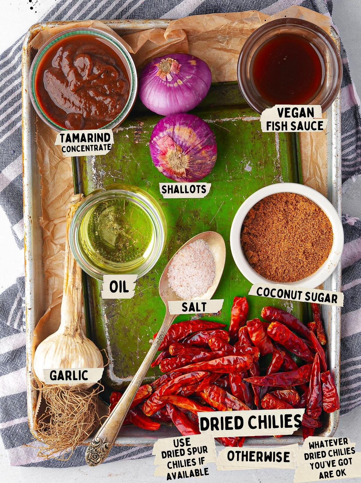 Ingredients on a tray: tamarind concentrate, vegan fish sauce, shallots, coconut sugar, oil, salt, garlic, dried chilies-all essentials for crafting a delectable Nam Prik Pao.