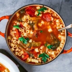 A pot of Escarole and Bean Soup with a spoon.