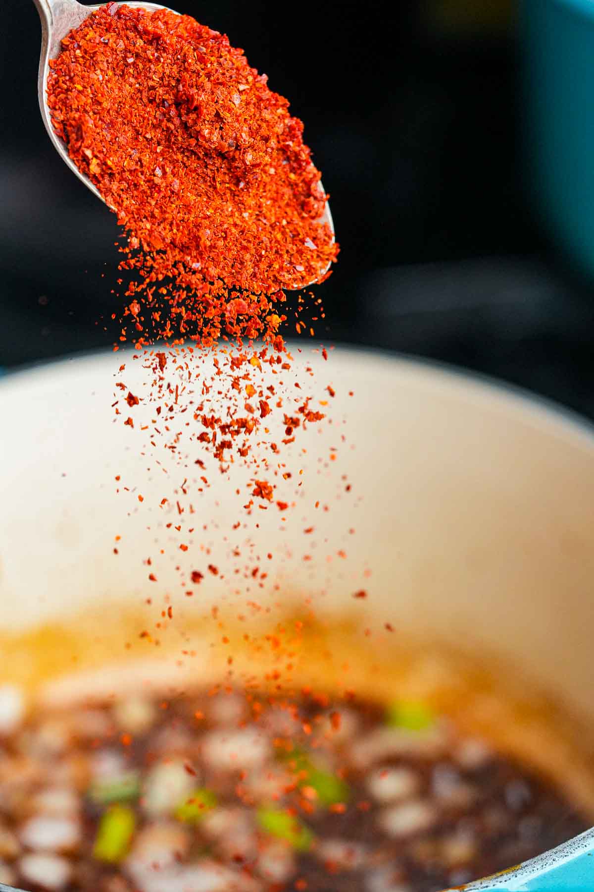 A spoonful of Korean chili powder being poured into a pot.