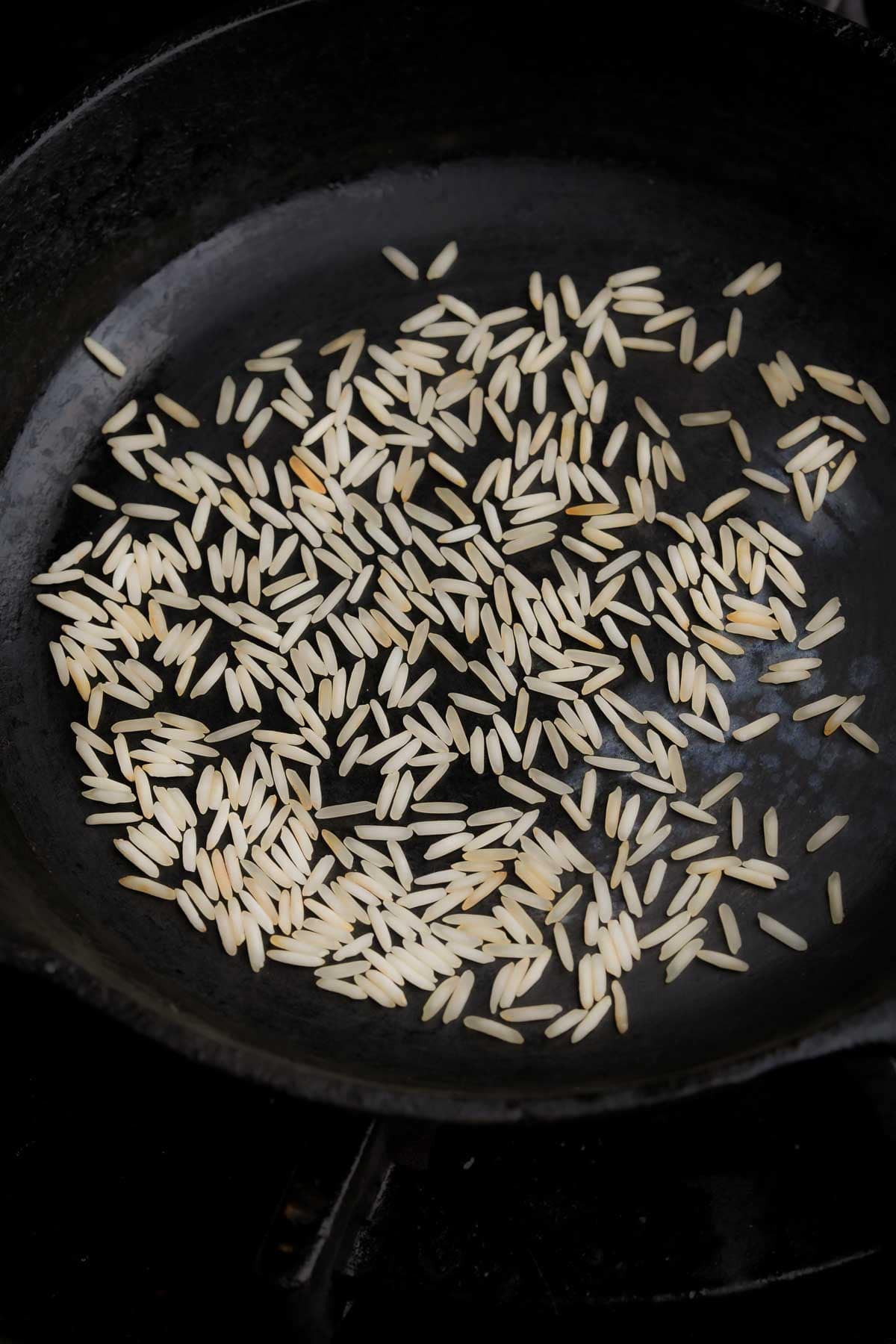 Toasting jasmine rice in a dry skillet on a stove.