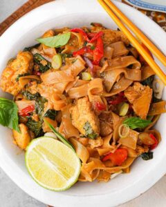 Thai Pad Kee Mao in a white bowl with chopsticks.
