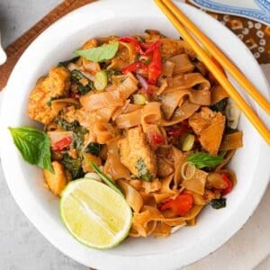 Thai Pad Kee Mao in a white bowl with chopsticks.