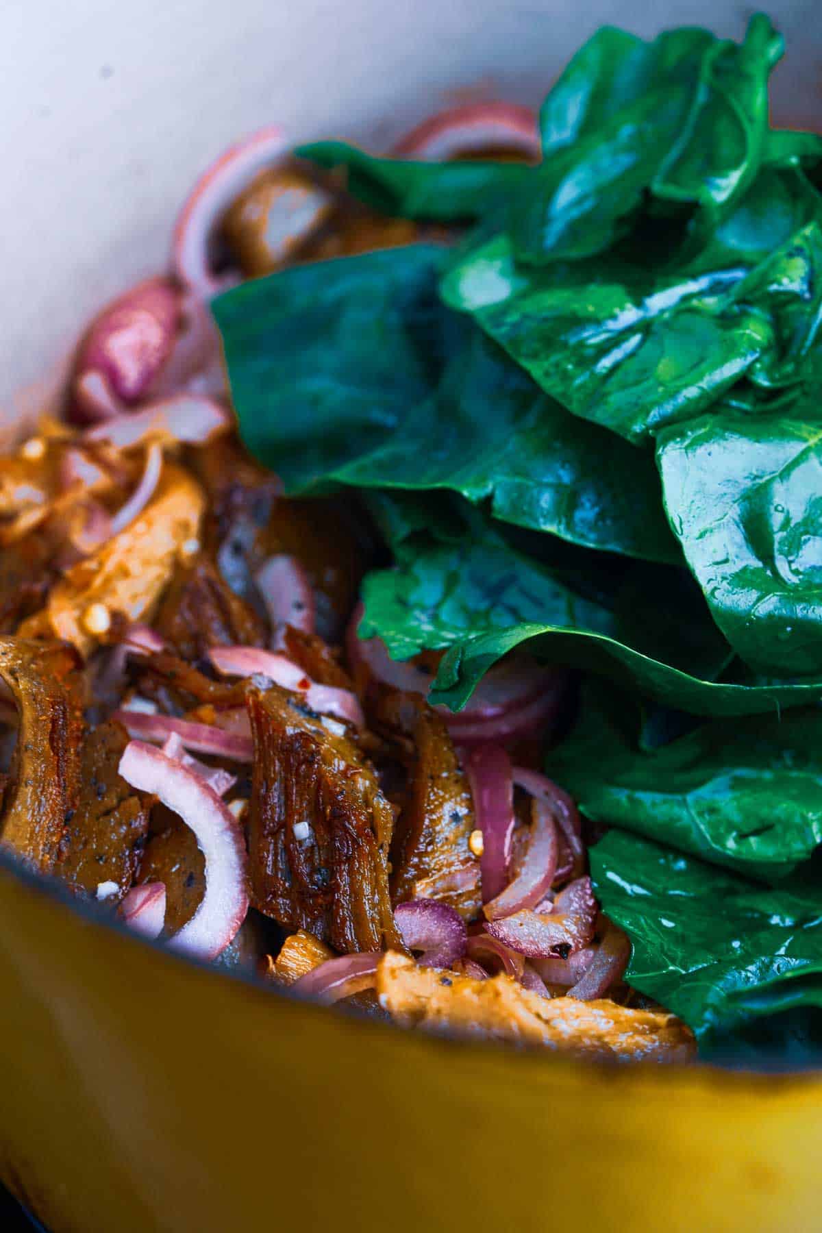 A pot of seitan and vegetables on a stove top.