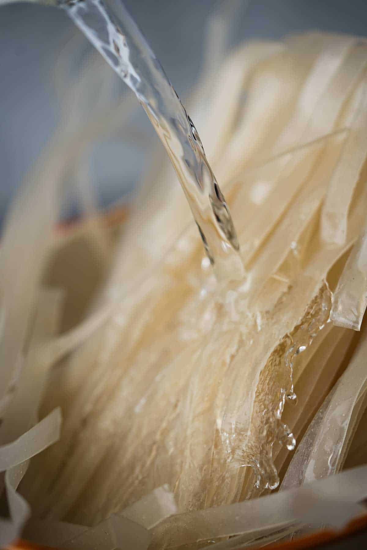 Water being poured into a bowl of dried noodles.