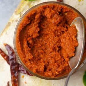A jar of red curry paste with a spoon.
