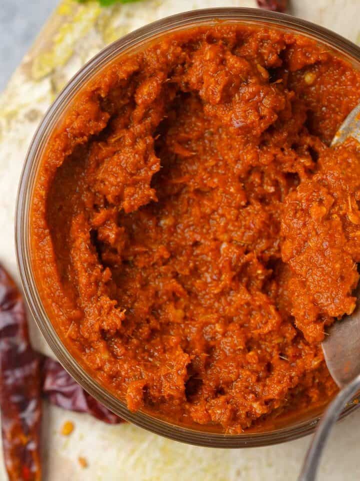 A jar of red curry paste with a spoon.