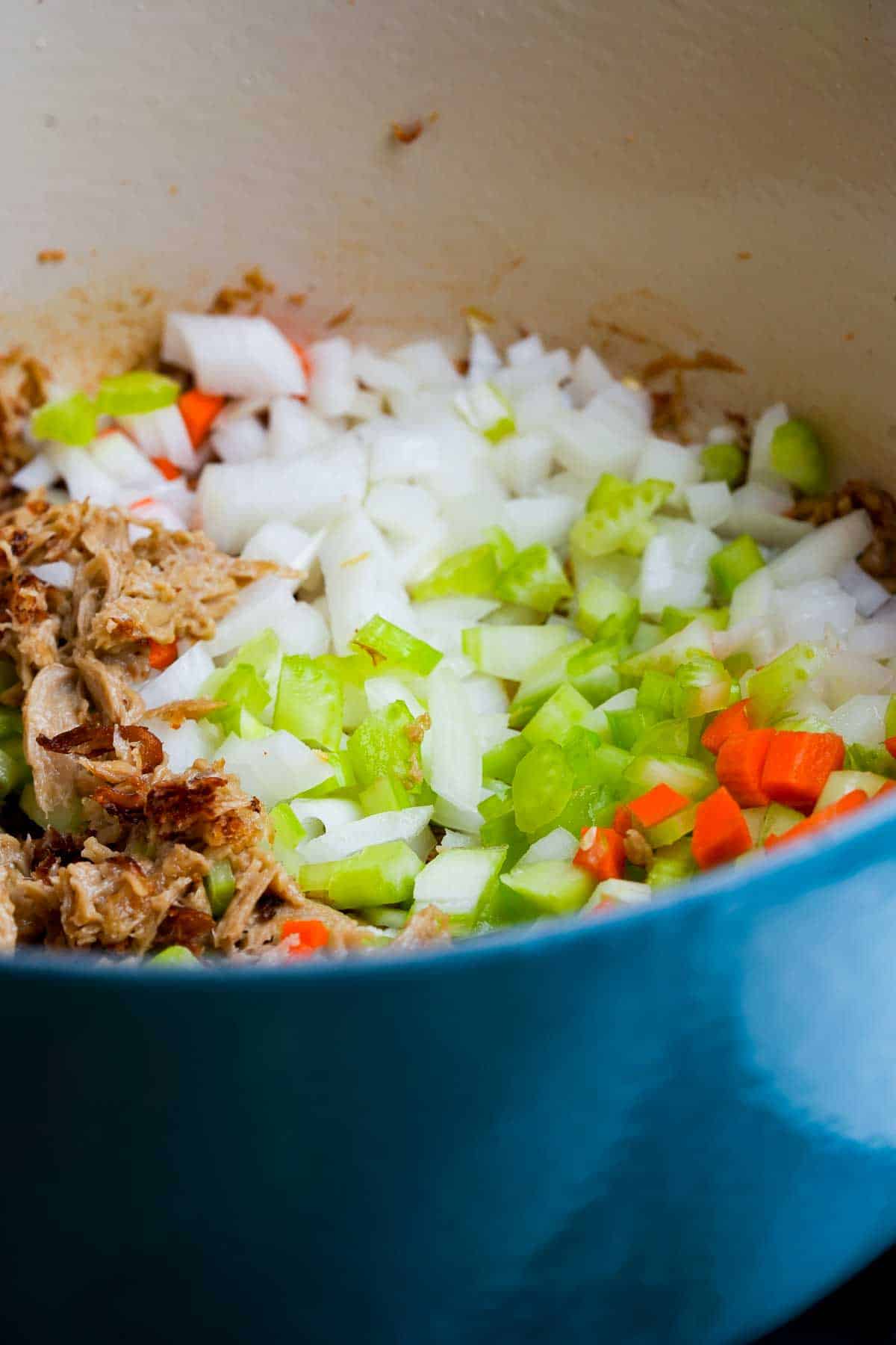A blue pot with seitan, celery, onions and carrots in it.