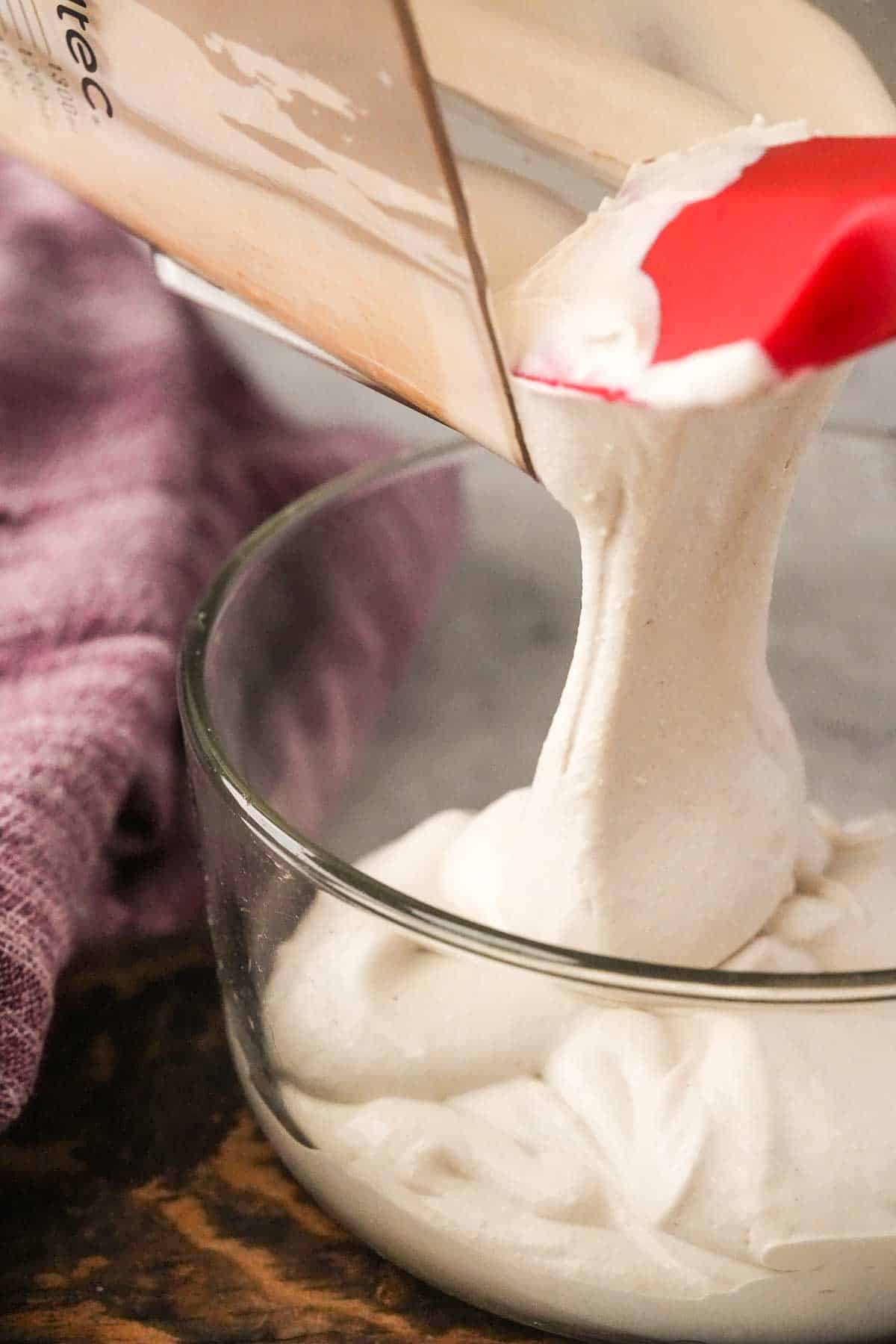 Whipped cashew cream being poured into a bowl.