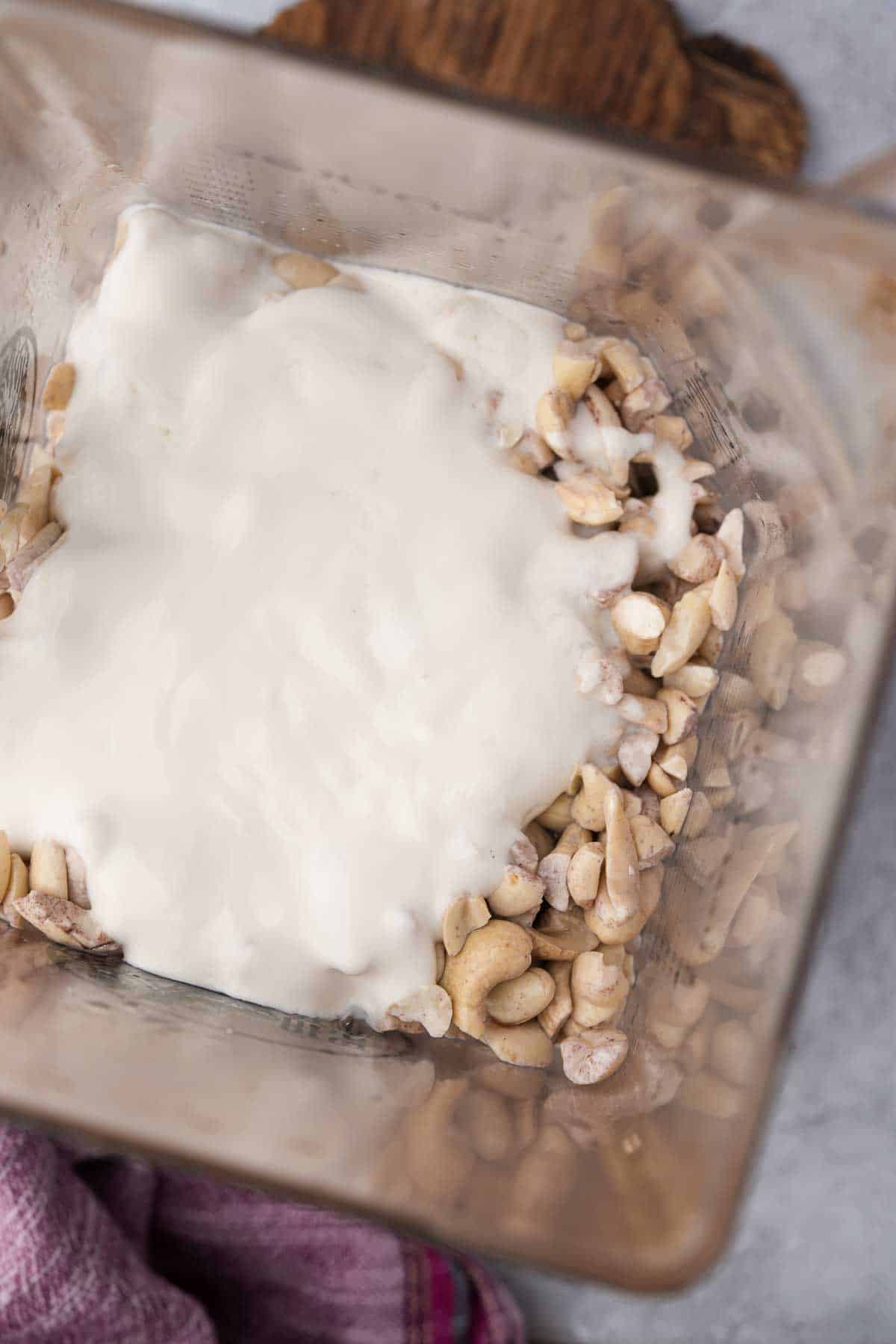 Cashew cream in a blender with water and vegan yogurt.