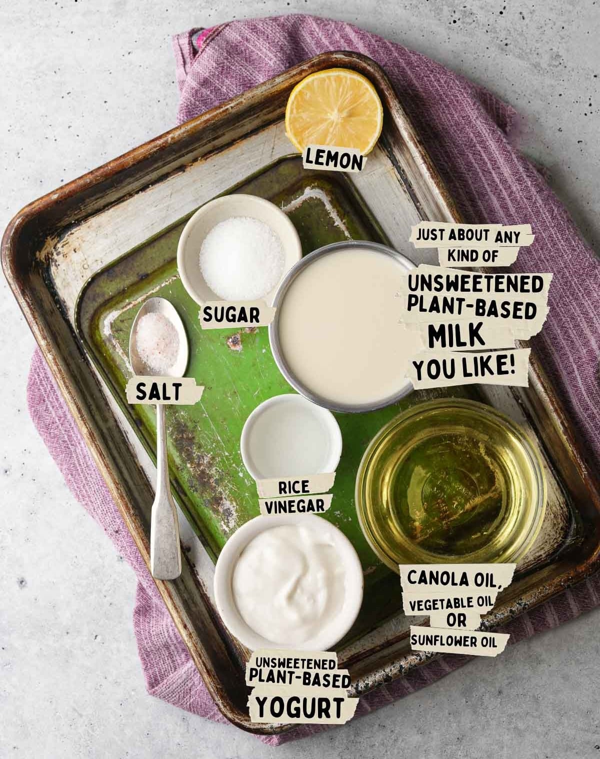 Ingredients for a recipe on a tray: lemon, sugar, salt, rice vinegar, unsweetened plant-based milk, canola oil, and vegan sour cream for that perfect tang.