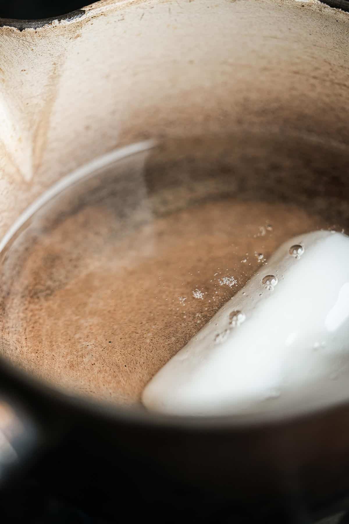A saucepan with a piece of coconut oil melting in it.
