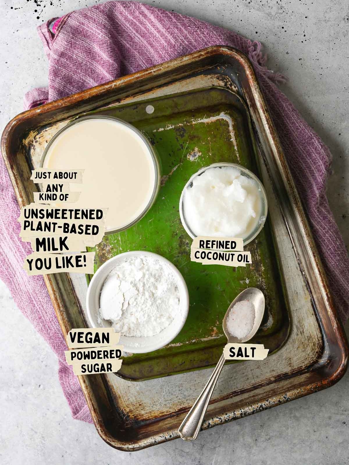 Ingredients on a tray for vegan whipped cream: unsweetened plant-based milk, refined coconut oil, vegan powdered sugar, and salt, with a purple cloth underneath.