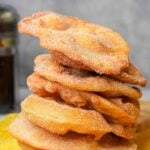 A stack of fried bunuelos on a yellow napkin.