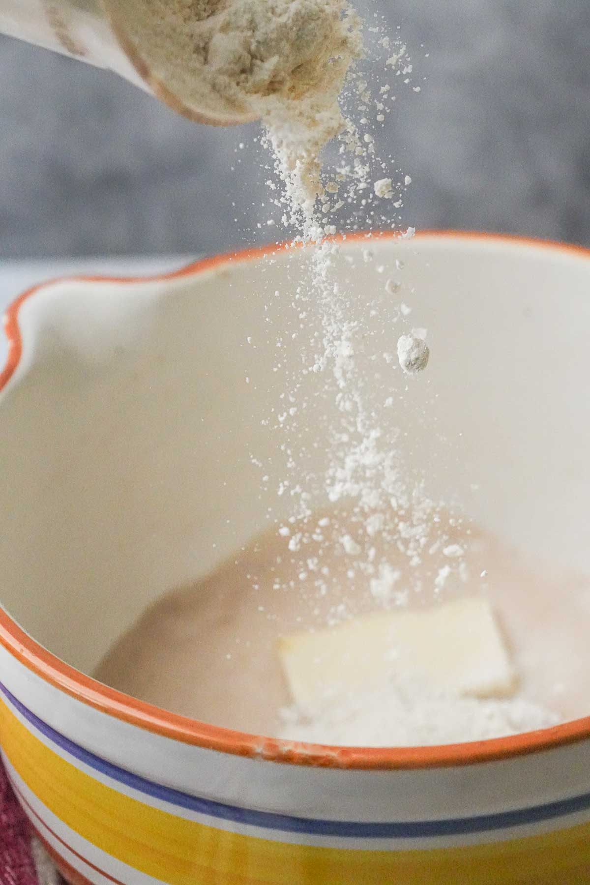 A person pouring flour into a mixing bowl.
