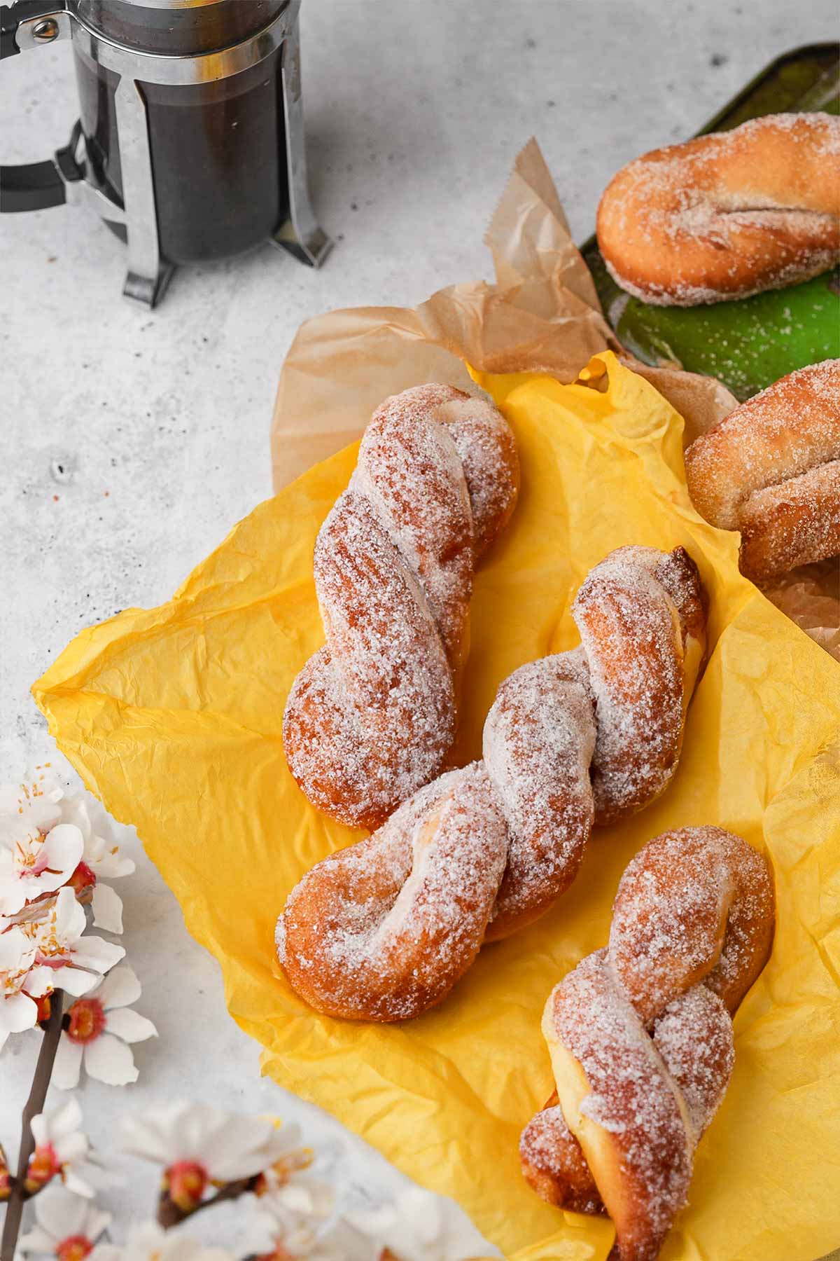 Sugared Korean twisted donuts with cherry blossoms on a yellow background.