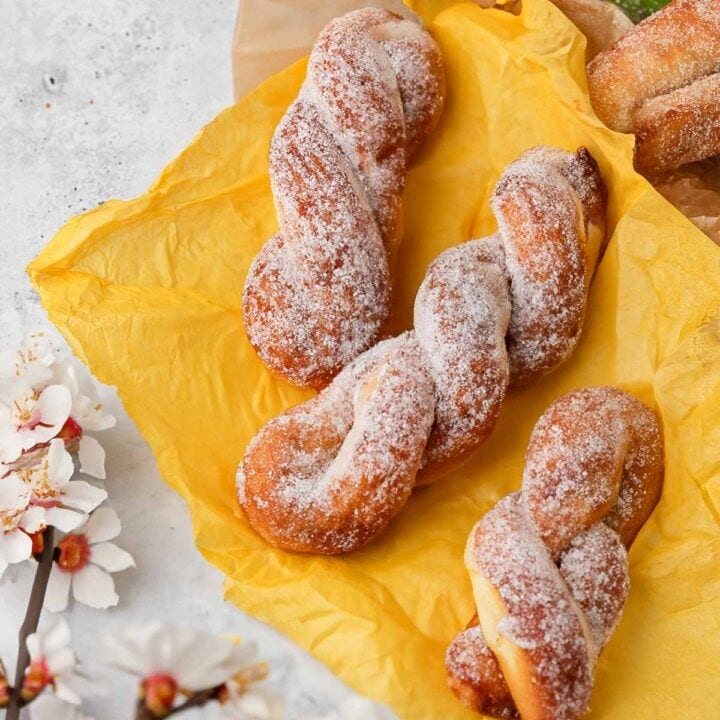 Sugared Korean twisted donuts with cherry blossoms on a yellow background.