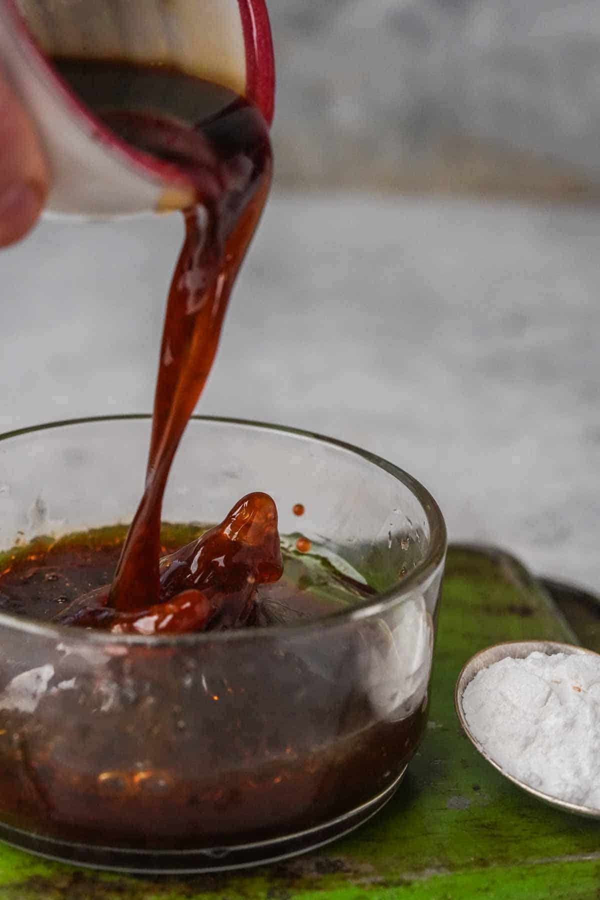 A person pouring a sauce into a bowl.