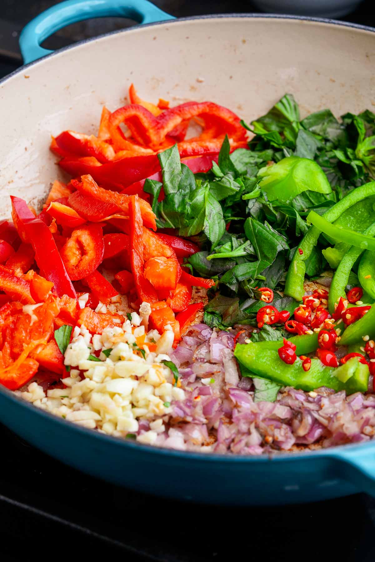 A pan with peppers, shallots, Thai basil, and other ingredients in it.