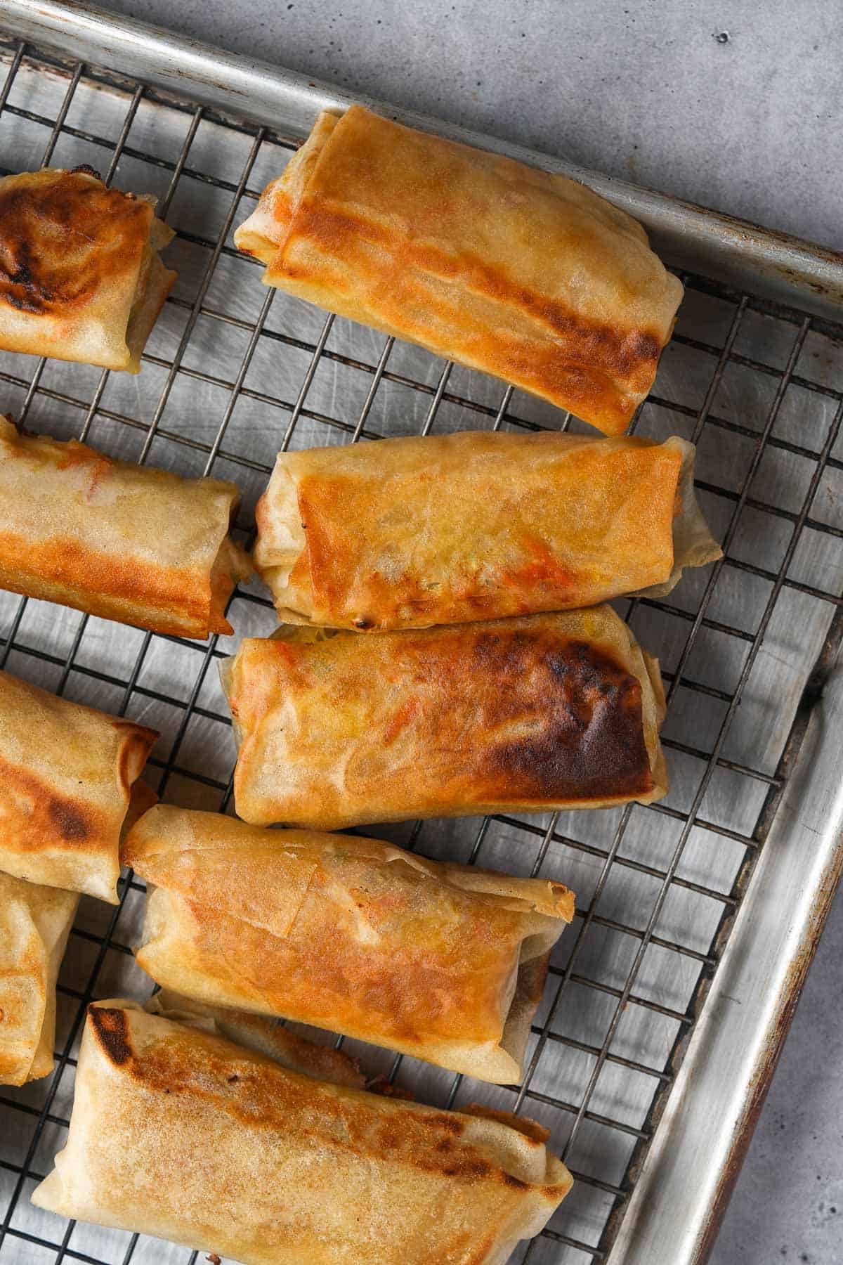 Fried spring rolls on a cooling rack.