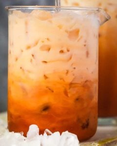 A cup of iced Thai tea with a straw.