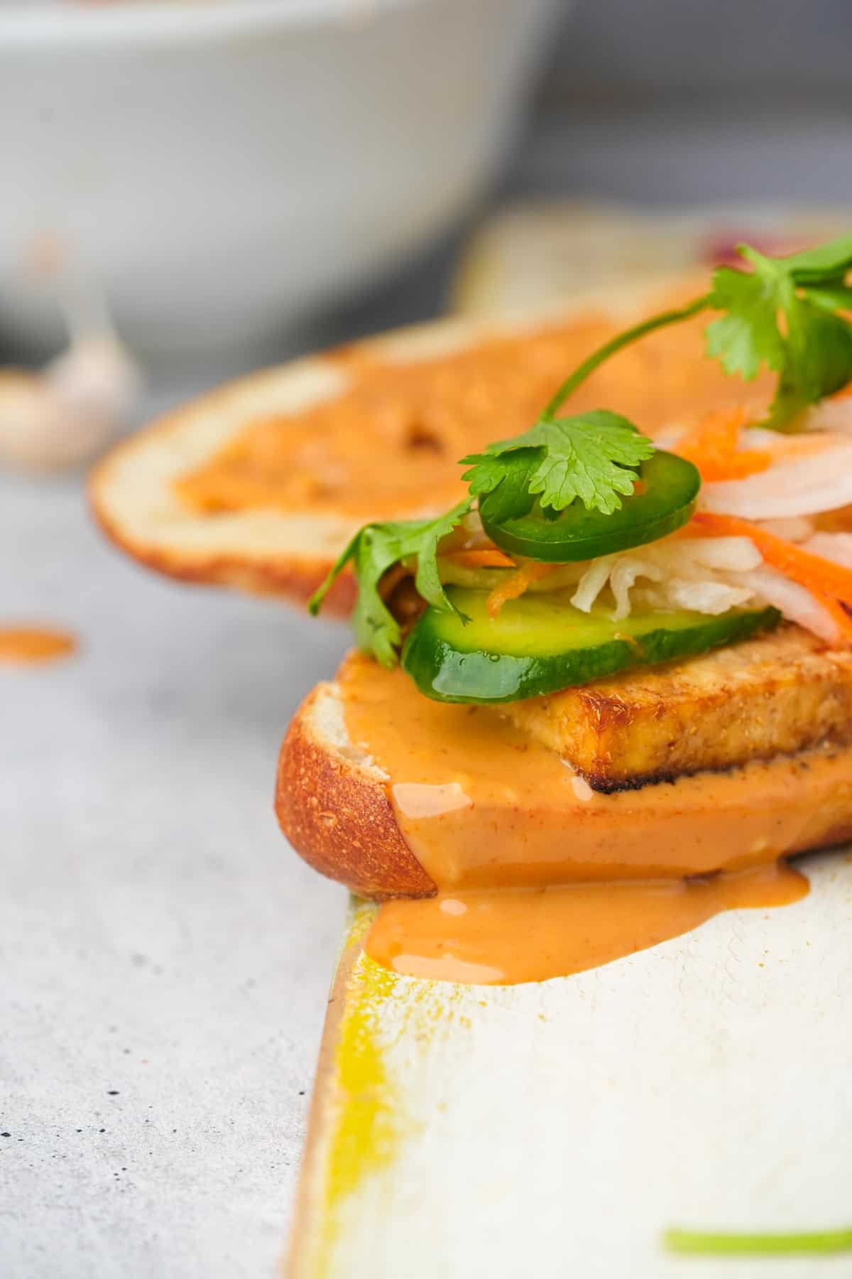 A vegan banh mi sandwich with sauce dripping out of it.