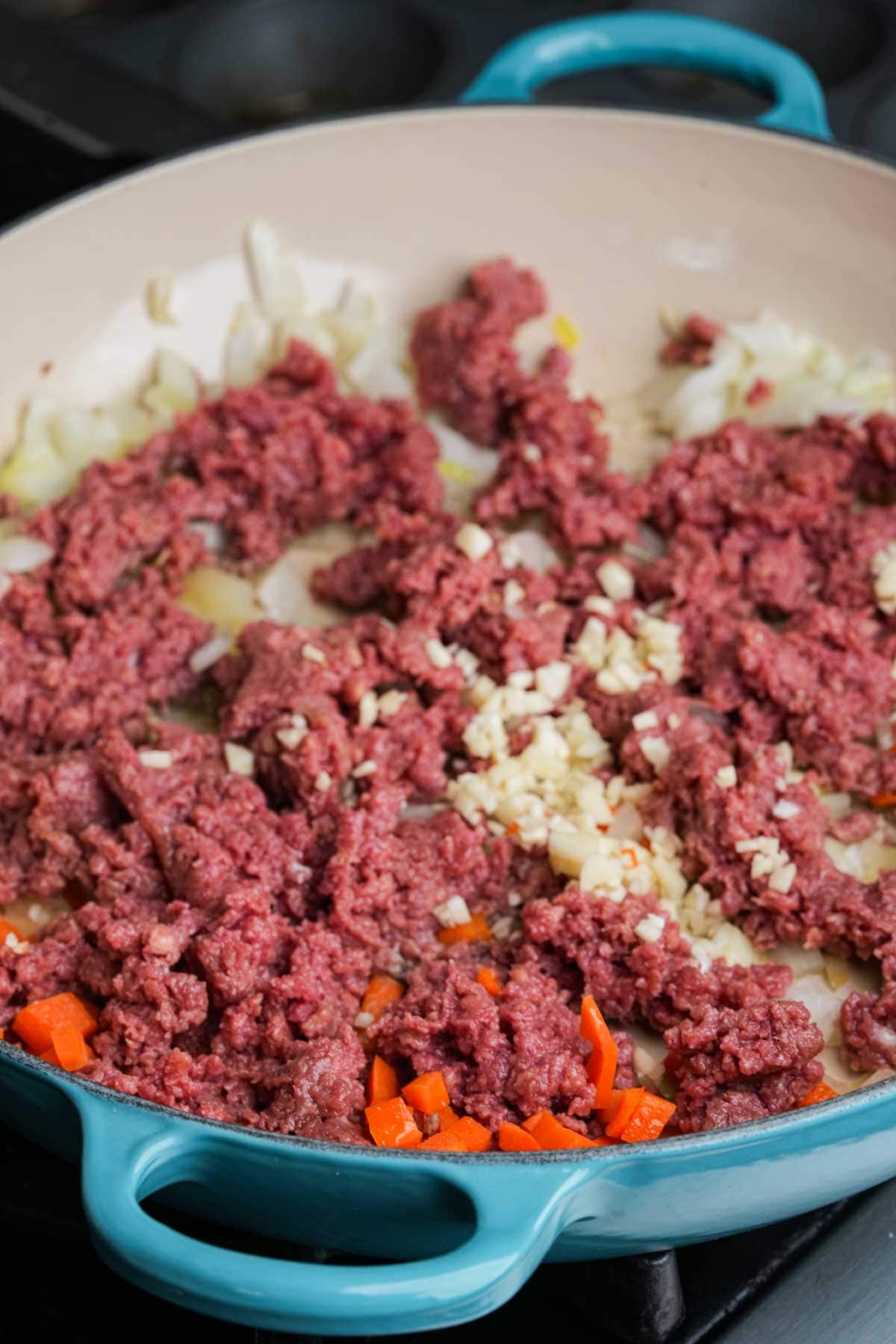 Vegan ground beef in a skillet with onions, garlic, and carrots.