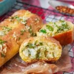 A loaf of vegan garlic bread with cheese and herbs on it.