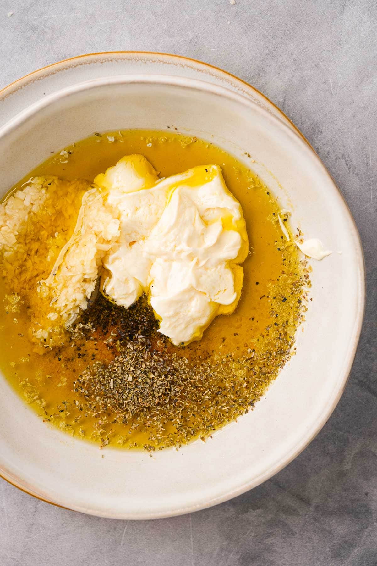 A white bowl with soft vegan butter, herbs, garlic, olive oil and spices.