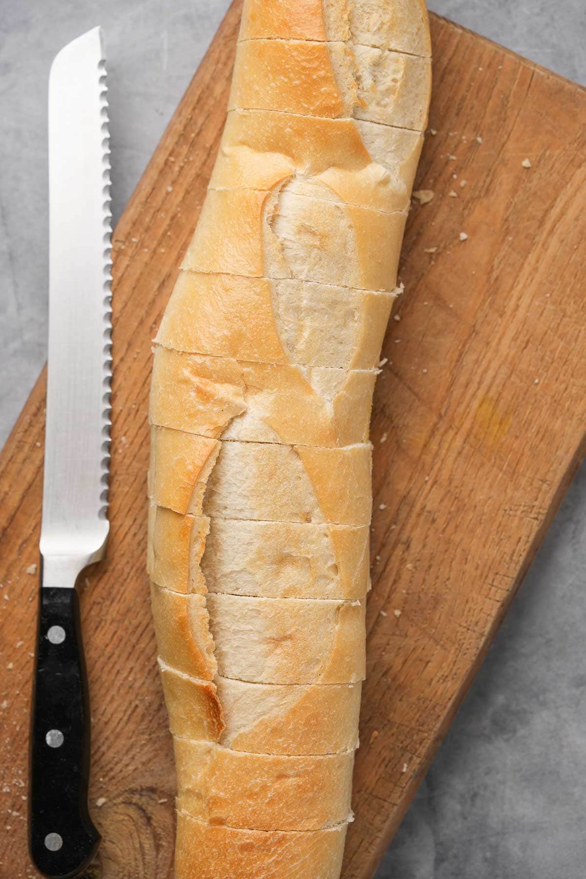 A loaf of bread on a cutting board with a knife.